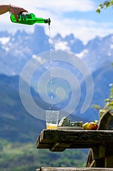 Pouring from high height of natural Asturian cider made fromÂ fermented apples, Asturian cabrales cow blue cheese with view on